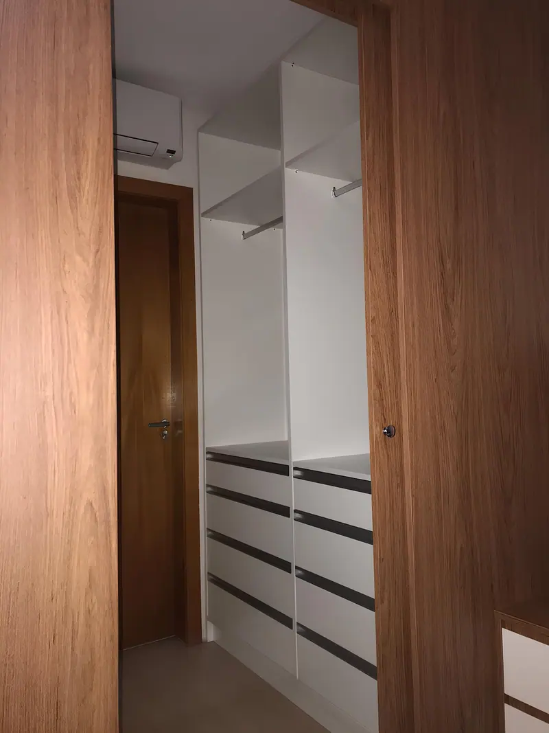 Closet aberto com gaveteiro, cabideiros e portas em madeira