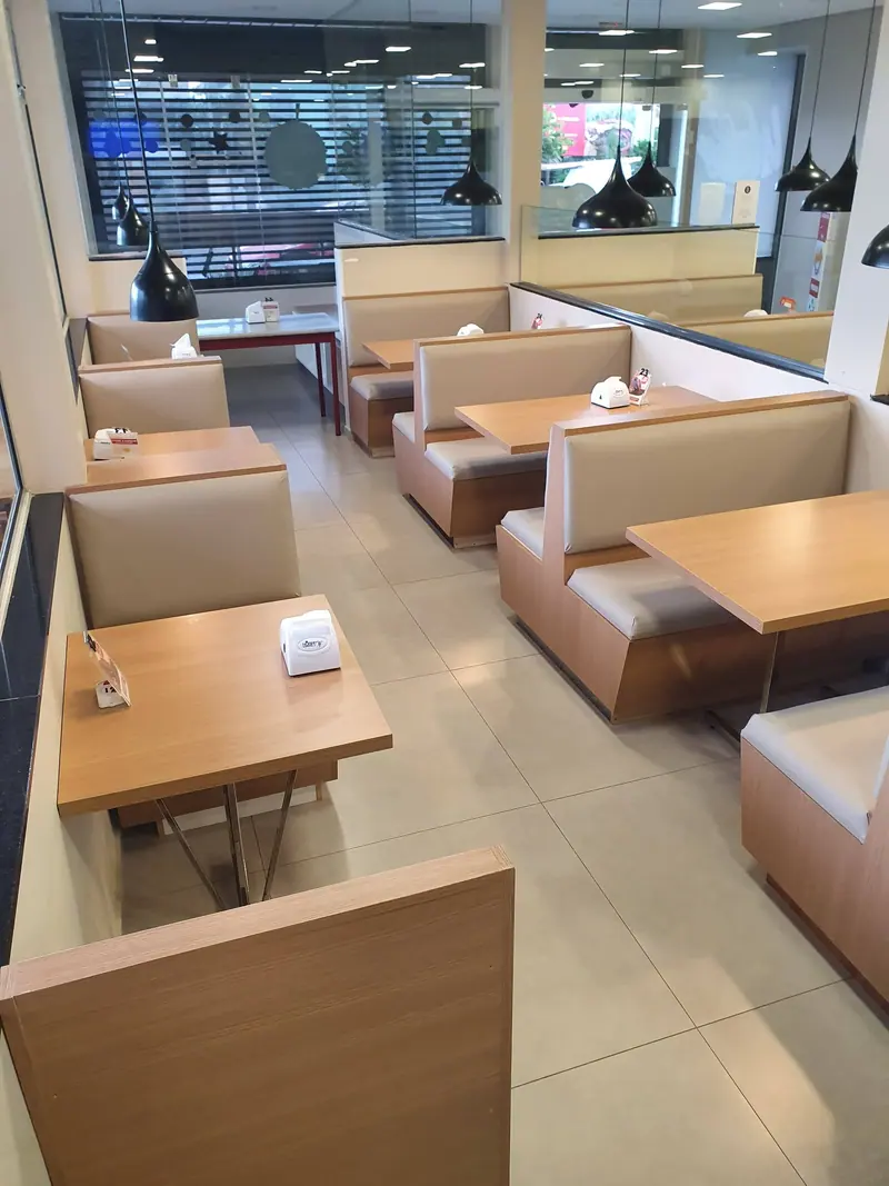 Ambiente comercial com cabines estofadas e mesas de madeira