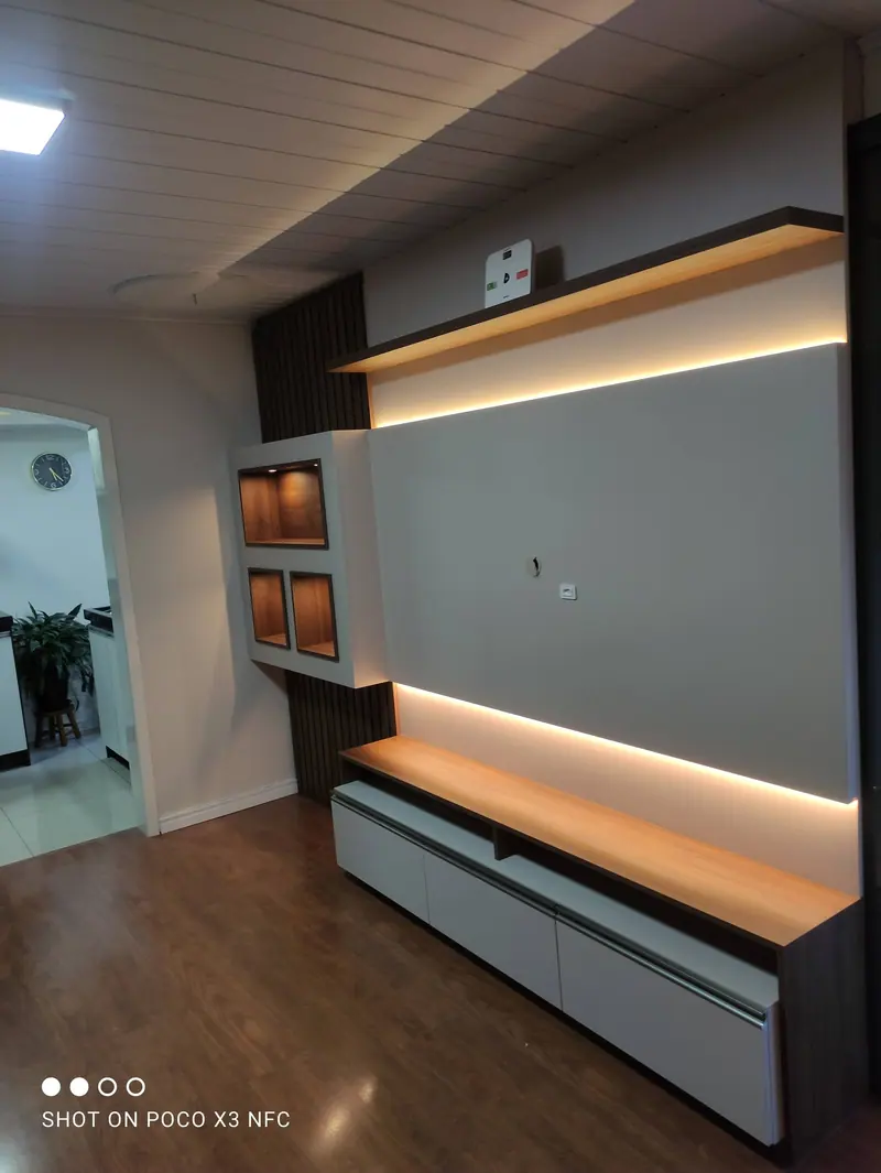 Painel de TV cinza com prateleiras de madeira iluminadas e rack suspenso